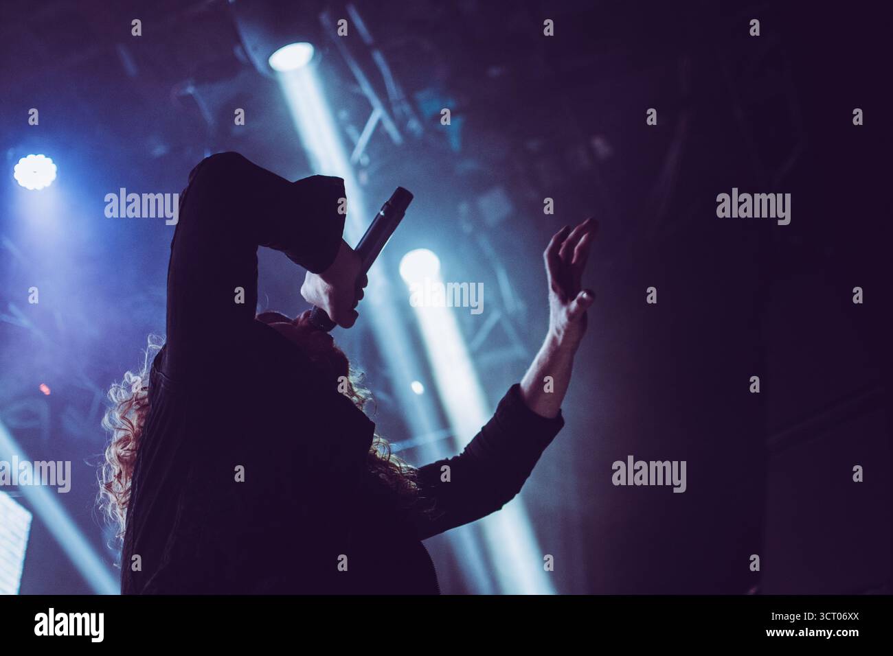 Metal vocalist performing passionately on stage during a club show, with colorful dramatic lighting Stock Photo