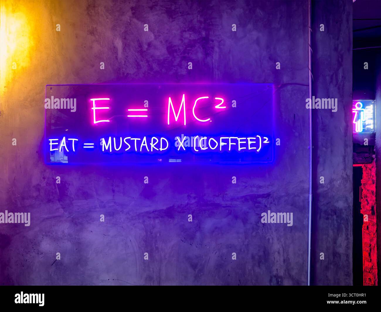 Neon sign on a concrete wall humorously combines a physics equation E=MC2 with an unconventional culinary formula restaurant   ipoh malaysia - Smartphone Captured Stock Image