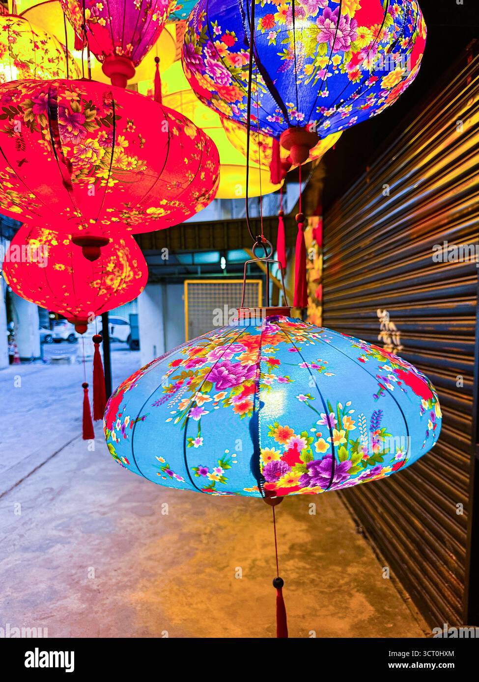 Colorful floral-patterned lanterns hanging in a row at a street market during a festival celebration at night ipoh malaysia - Smartphone Captured Stock Image