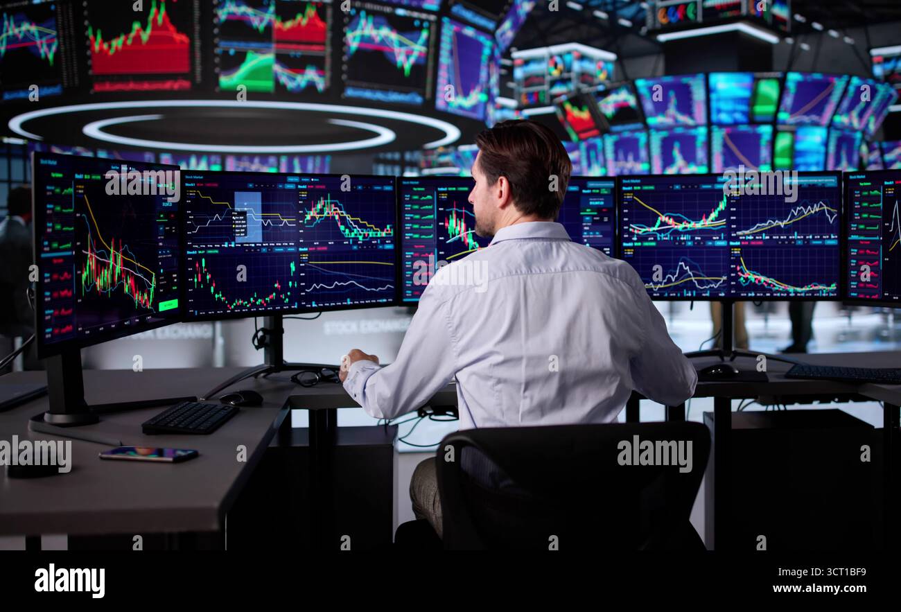 Senior Trader Analyzing Stock Market Data On Multiple Computer Screens. Stock Photo