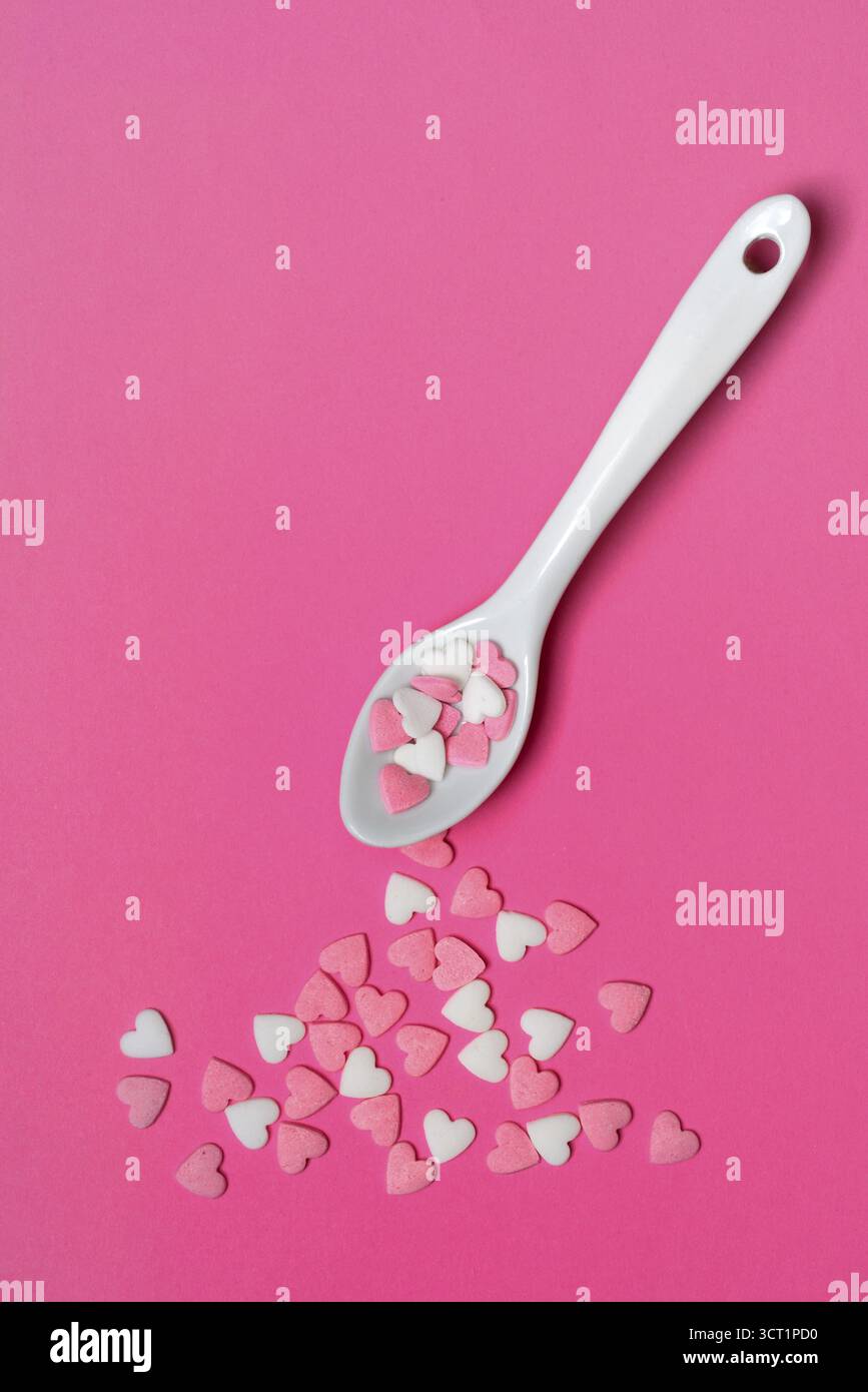 Sugar hearts with spoon on pink background Stock Photo