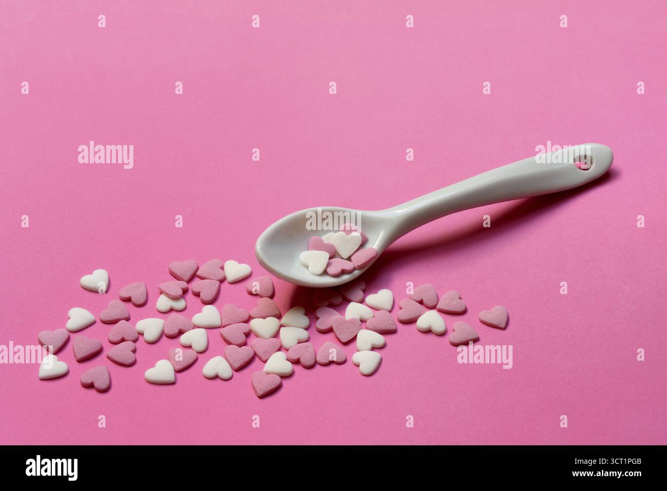 Sugar hearts with spoon on pink background Stock Photo
