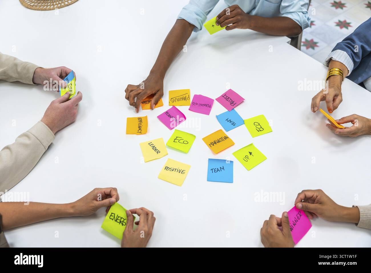 Diverse business professionals collaborating on a project, sharing ideas, and developing strategies during a meeting, arranging colorful sticky notes Stock Photo