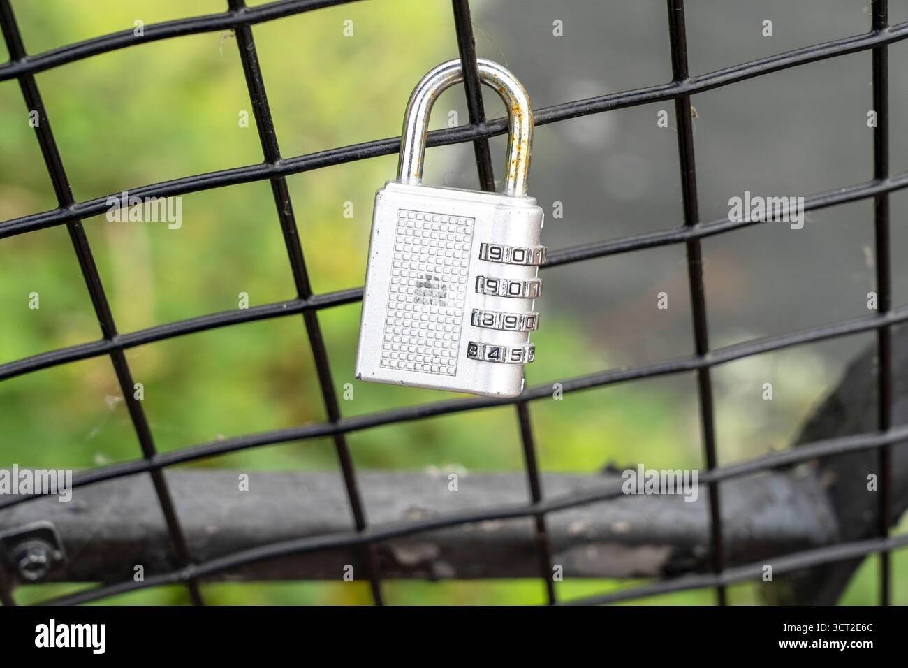 Combination padlock hanging on wire fence Stock Photo