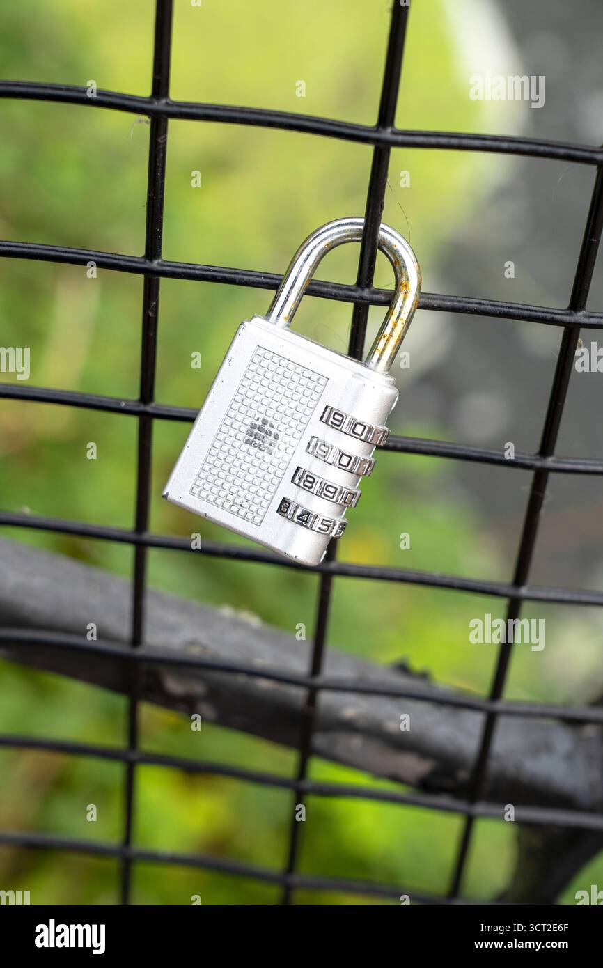 Combination padlock hanging on wire fence Stock Photo