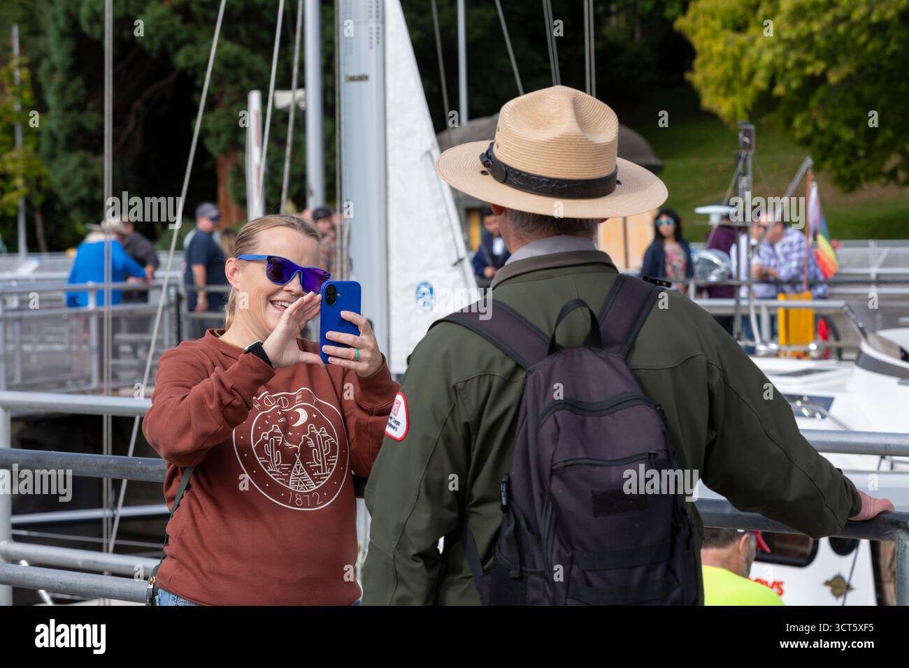 Seattle, Washington, USA. 4th October 2025. A visitor takes a video of Park Ranger Peter Lundberg speaking at the Hiram M. Chittenden Locks. The Ballard Locks, as they are known locally, are a popular tourist attraction operated by the United States Army Corps of Engineers. Though currently open the public during the government shutdown, the site’s visitor center, gardens and park rangers are at present funded with appropriations for the next two weeks. Credit: Paul Christian Gordon/Alamy Live News Stock Photo
