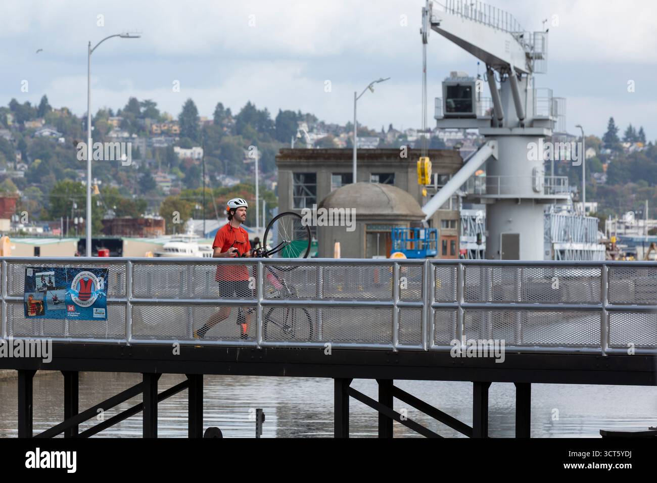 Seattle, Washington, USA. 4th October 2025. A young cyclist walks his bike over one of the gates at the Hiram M. Chittenden Locks. The Ballard Locks, as they are known locally, are a popular tourist attraction operated by the United States Army Corps of Engineers. Though currently open the public during the government shutdown, the site’s visitor center, gardens and park rangers are at present funded with appropriations for the next two weeks. Credit: Paul Christian Gordon/Alamy Live News Stock Photo