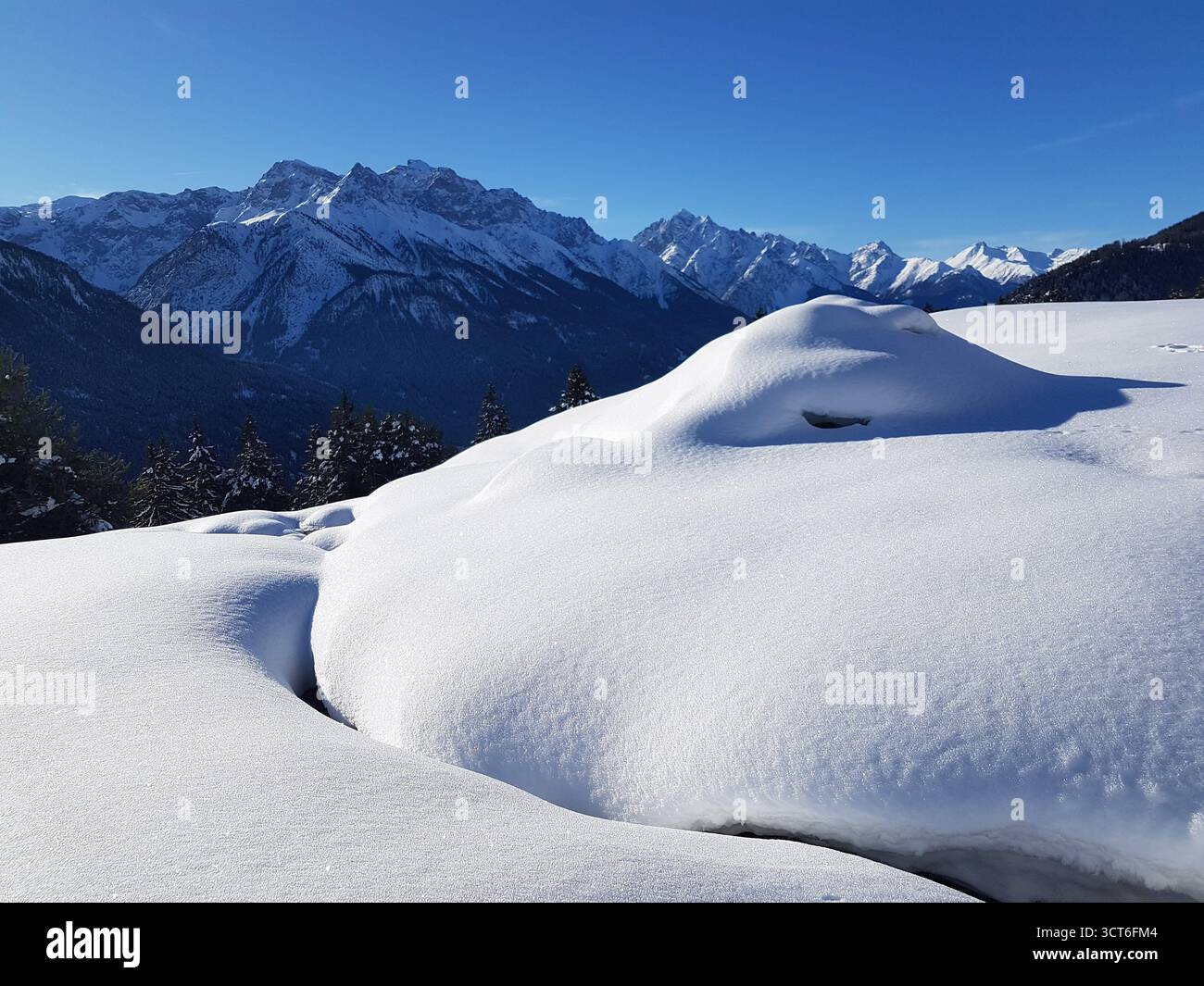 Idyllic and beautiful winter landscape in the Swiss Alps with lots of snow on a bright sunny winter day, Engadine, Switzerland Stock Photo