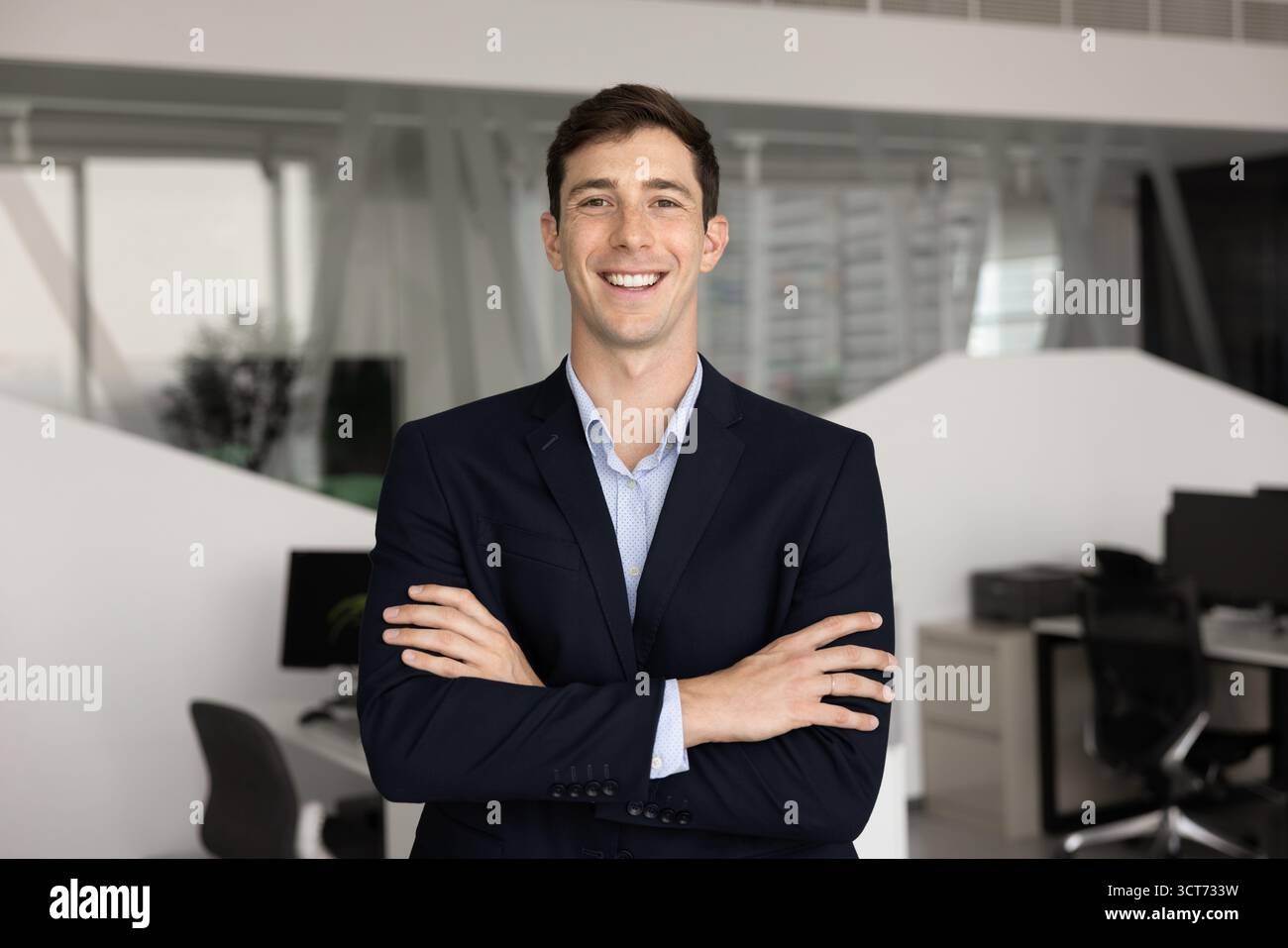 Positive young professional man posing on office with hands folded Stock Photo
