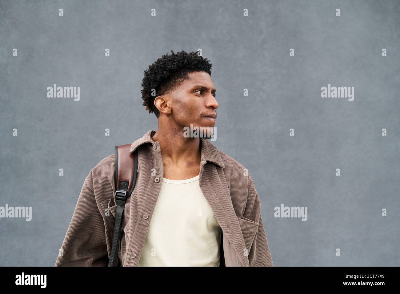 Young Black Man Standing Outdoors Looking Away with Backpack Stock Photo