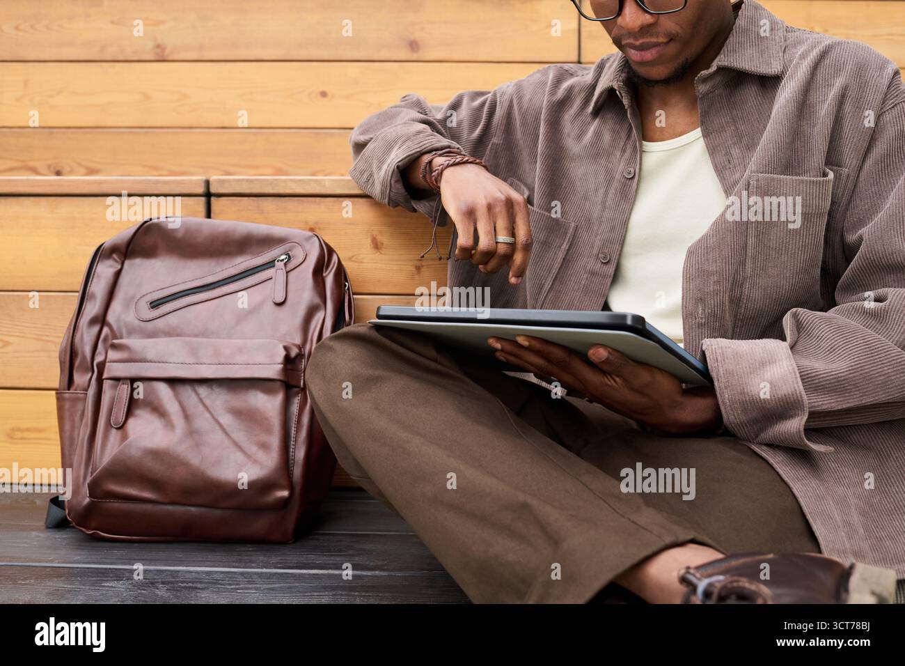 Young Black Man Sitting Outdoors Using Digital Tablet for Studying Stock Photo