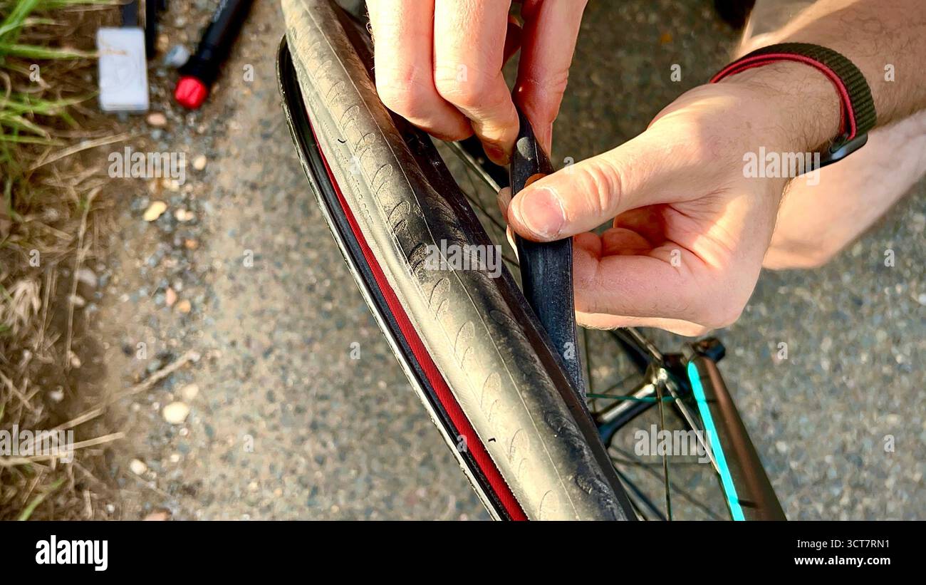 A close-up photograph of a man fixing a bicycle puncture, showing only his hands and part of the tyre. - Smartphone Captured Stock Image