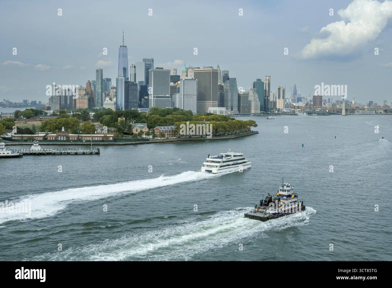 New York, NY, US - Sep 27, 2025 Ferries and boats cruise through the harbor near Governors Island with Lower Manhattan’s skyline and One World Trade C Stock Photo