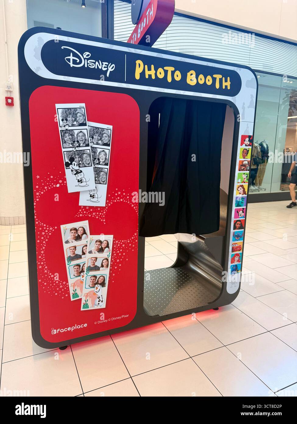 Red photo printing kiosk with sample photo strips on display stands indoors in New Orleans, Louisiana, USA, offering instant prints for visitors. - Smartphone Captured Stock Image