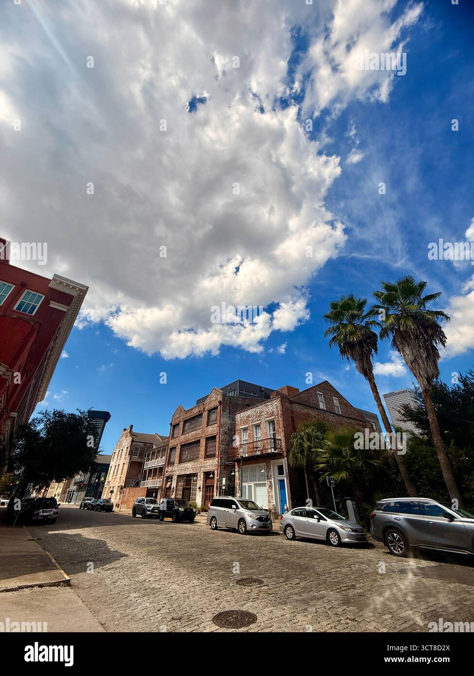 Cobbled street and historic brick buildings under dramatic clouds, New Orleans - Smartphone Captured Stock Image