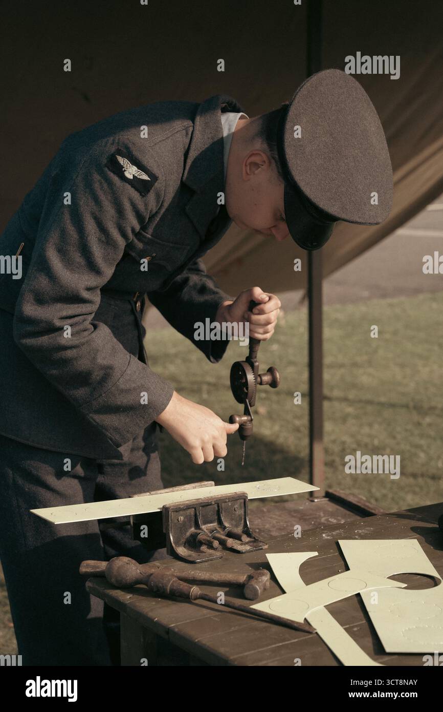 RAF serviceman in uniform drilling wood with hand tool at aircraft museum Stock Photo