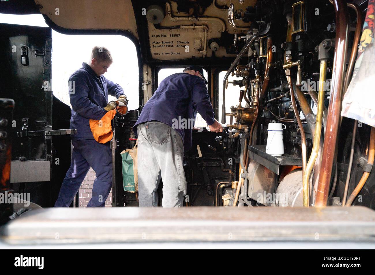 Steam locomotive crew working in engine cab with vintage controls and ...