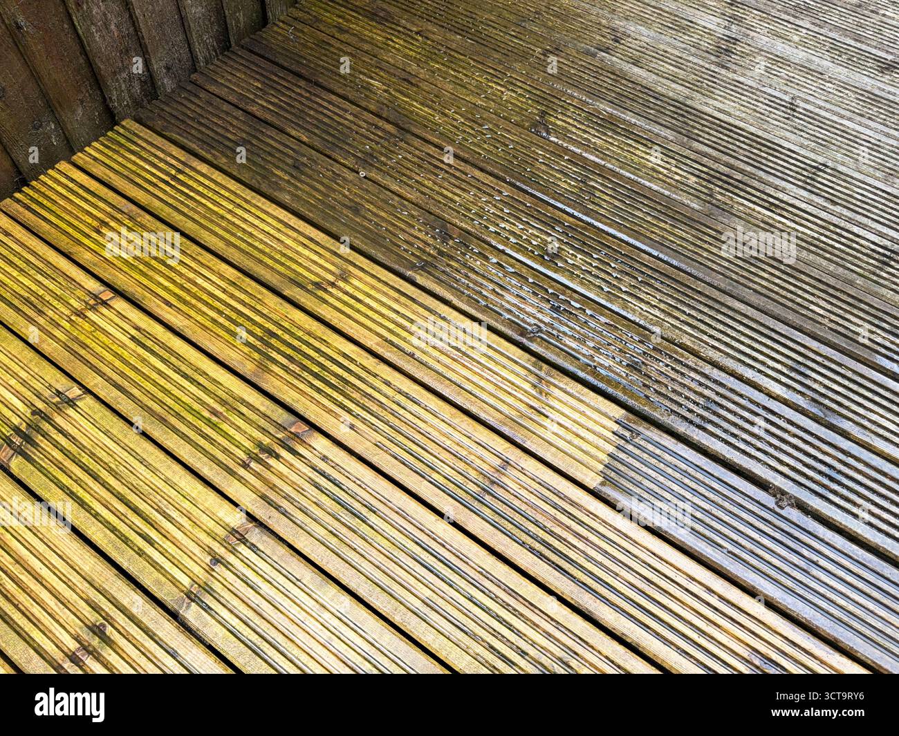 Before and after view of dirt and grime being cleaned from wooden decking using a pressure washer. DIY concept. - Smartphone Captured Stock Image