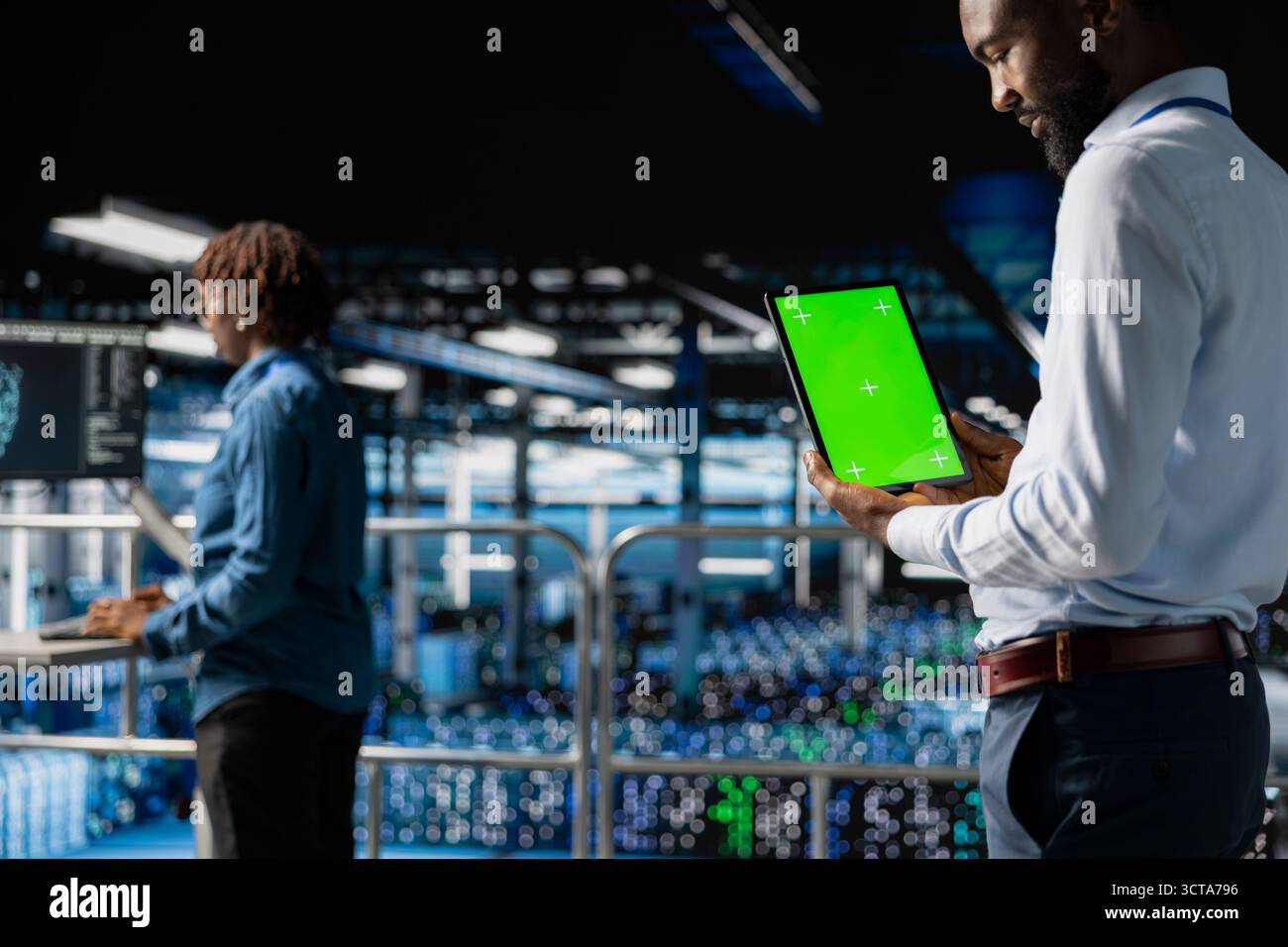 African american technician using copy space display on tablet, solving software development tasks on industrial platform. Young man visualizing infrastructure engineering in server room. Stock Photo