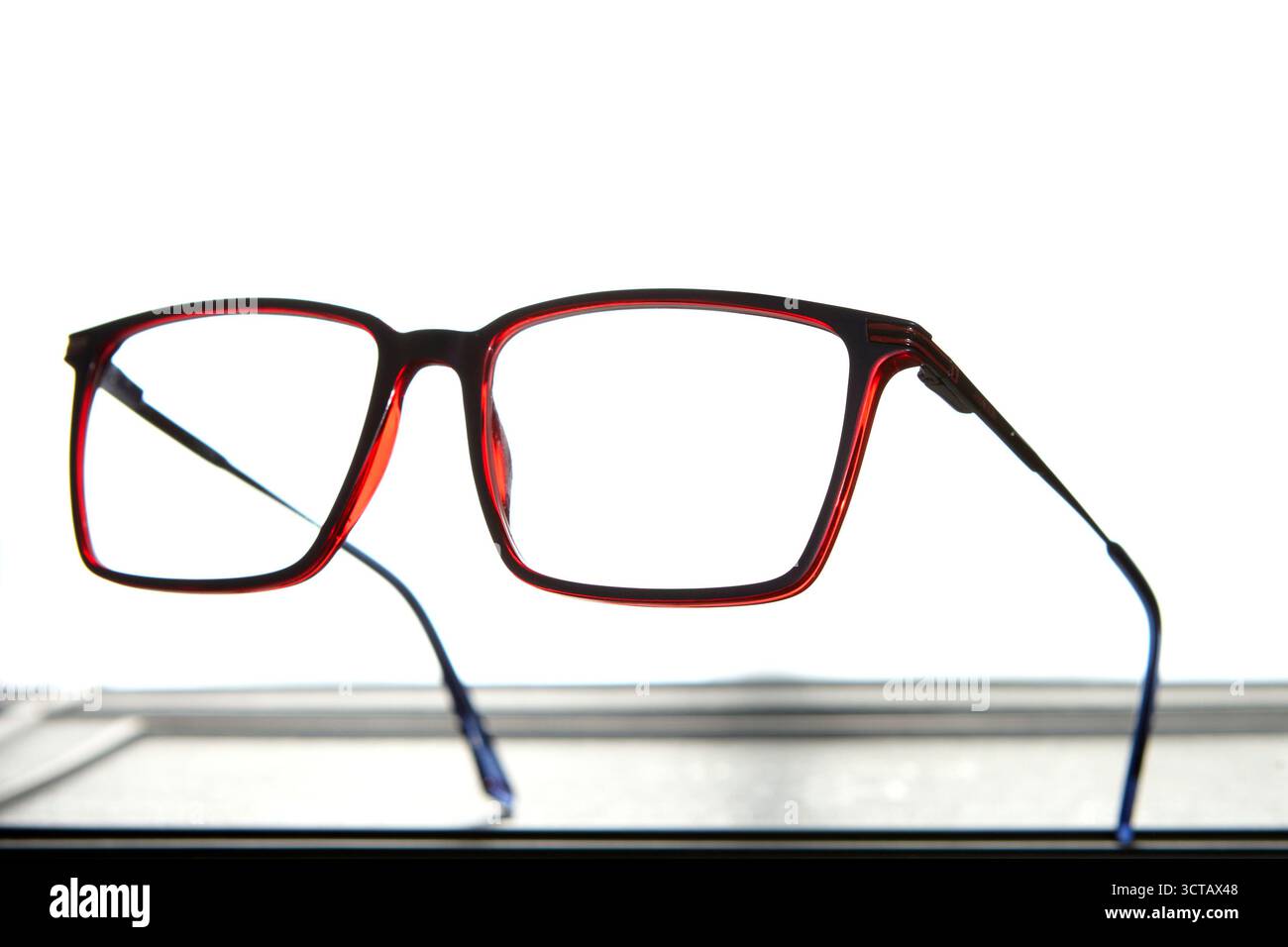 Studio photo of stylish red eyeglasses isolated on clean white background symbolizing modern fashion accessory and optical clarity for vision correcti Stock Photo