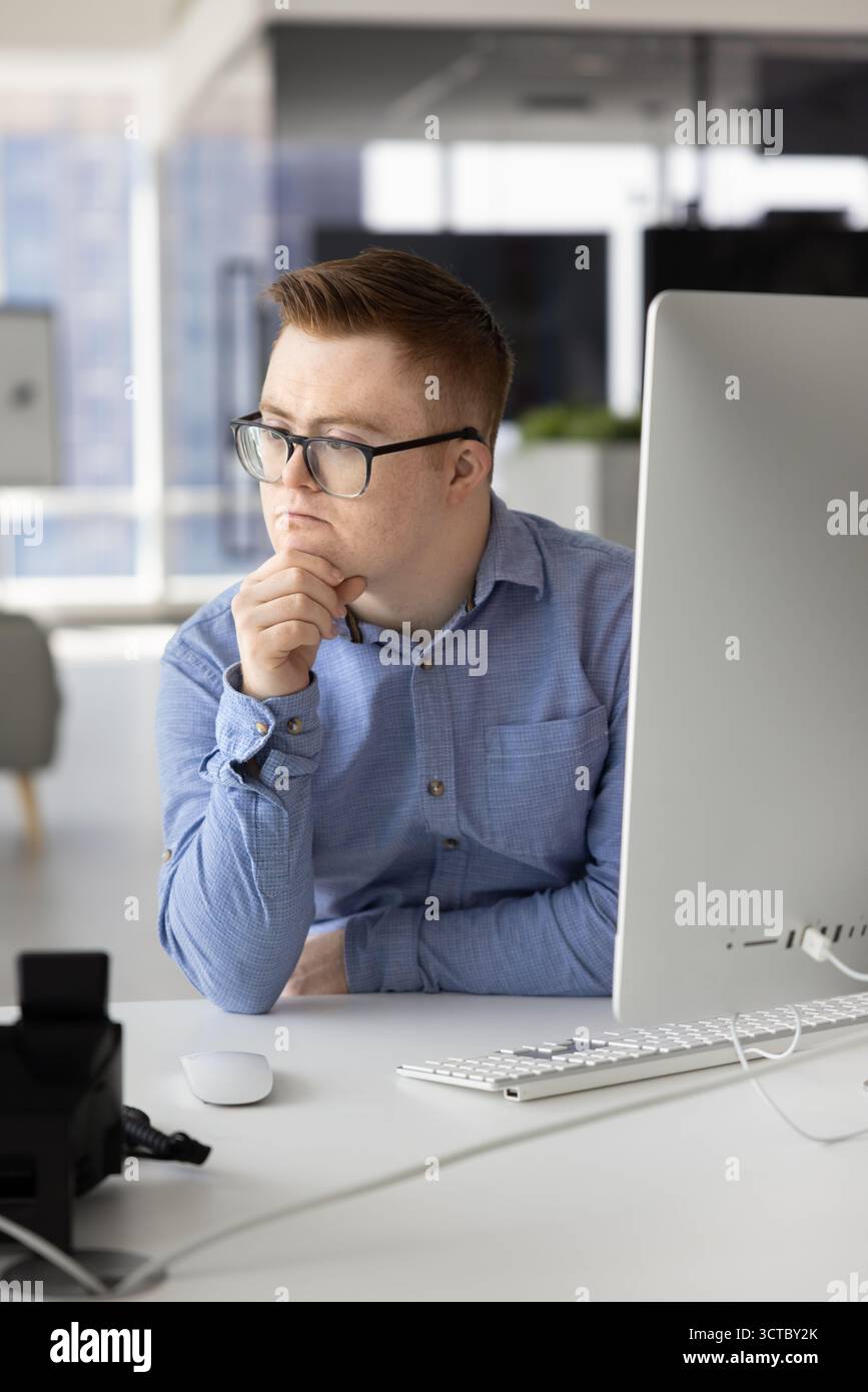 Thoughtful creative professional with Down syndrome thinking on ideas Stock Photo