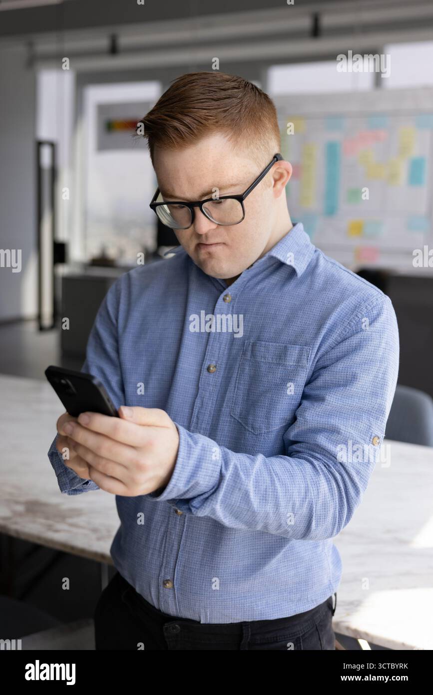 Focused male employee with Down syndrome using Internet technology Stock Photo