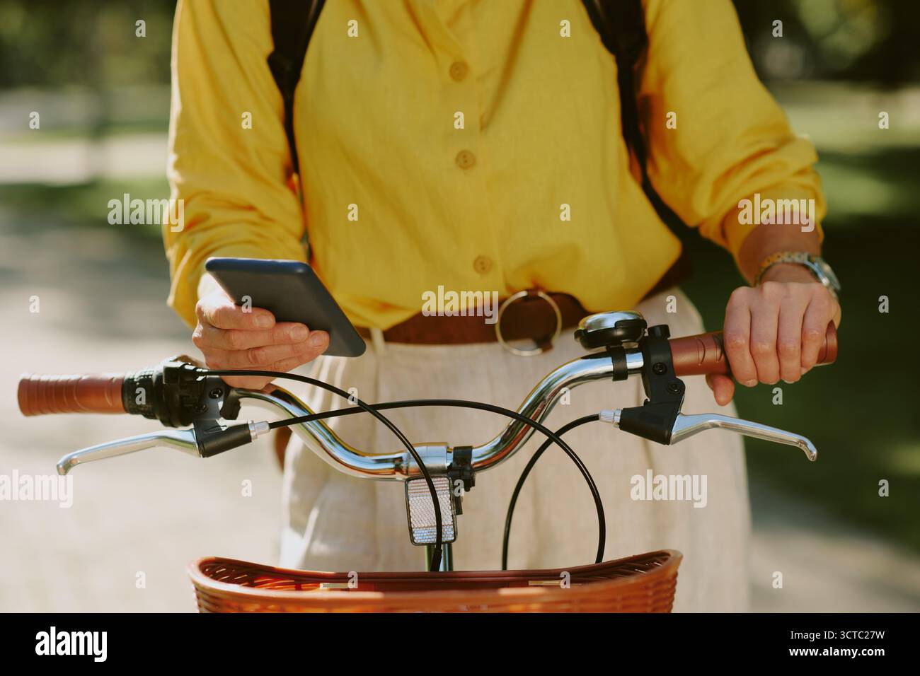 Middle Aged Caucasian Woman Using Smartphone While Holding Bicycle Outdoors Stock Photo