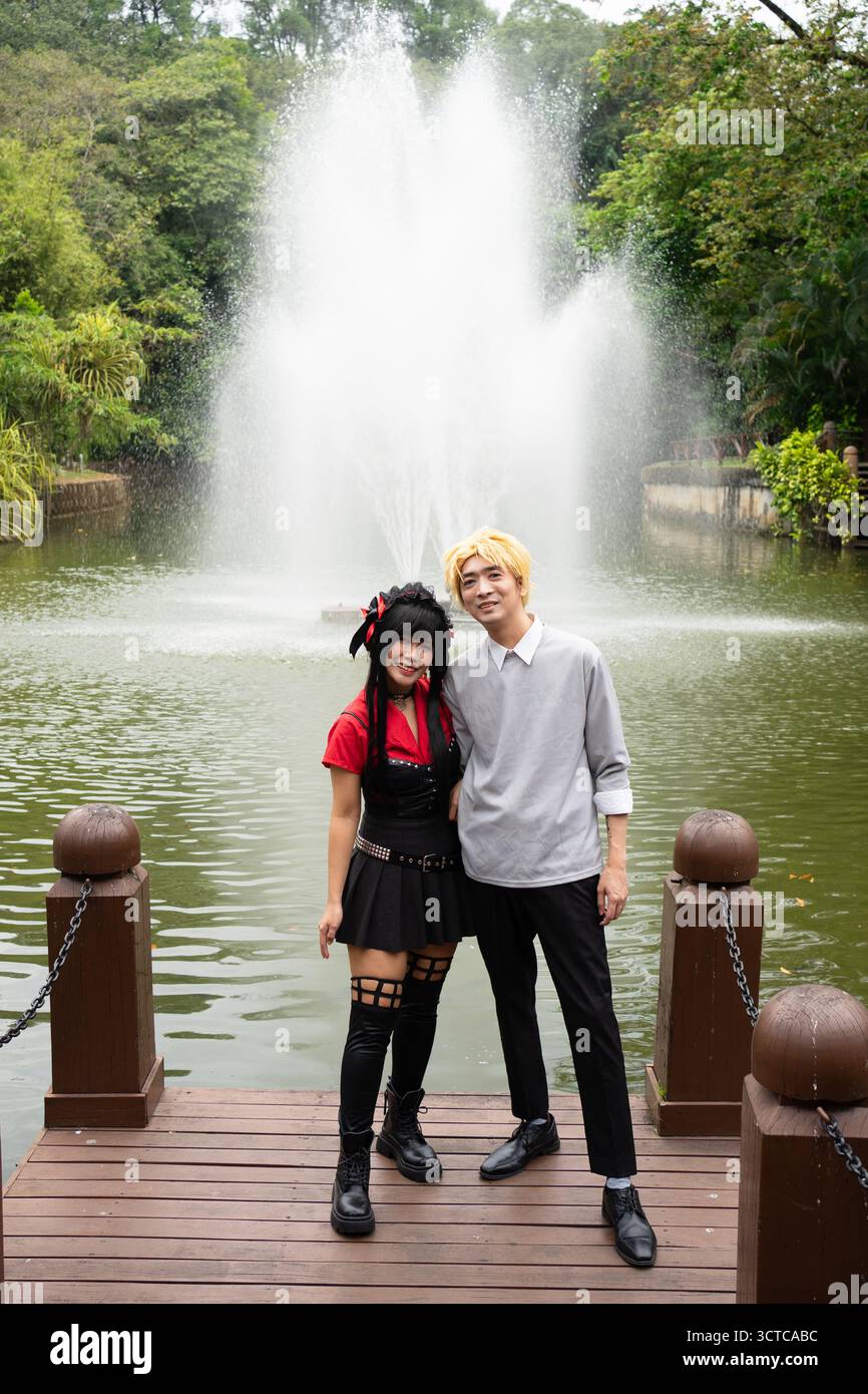 Two cosplayers are posing on a pier with a fountain in the background Stock Photo