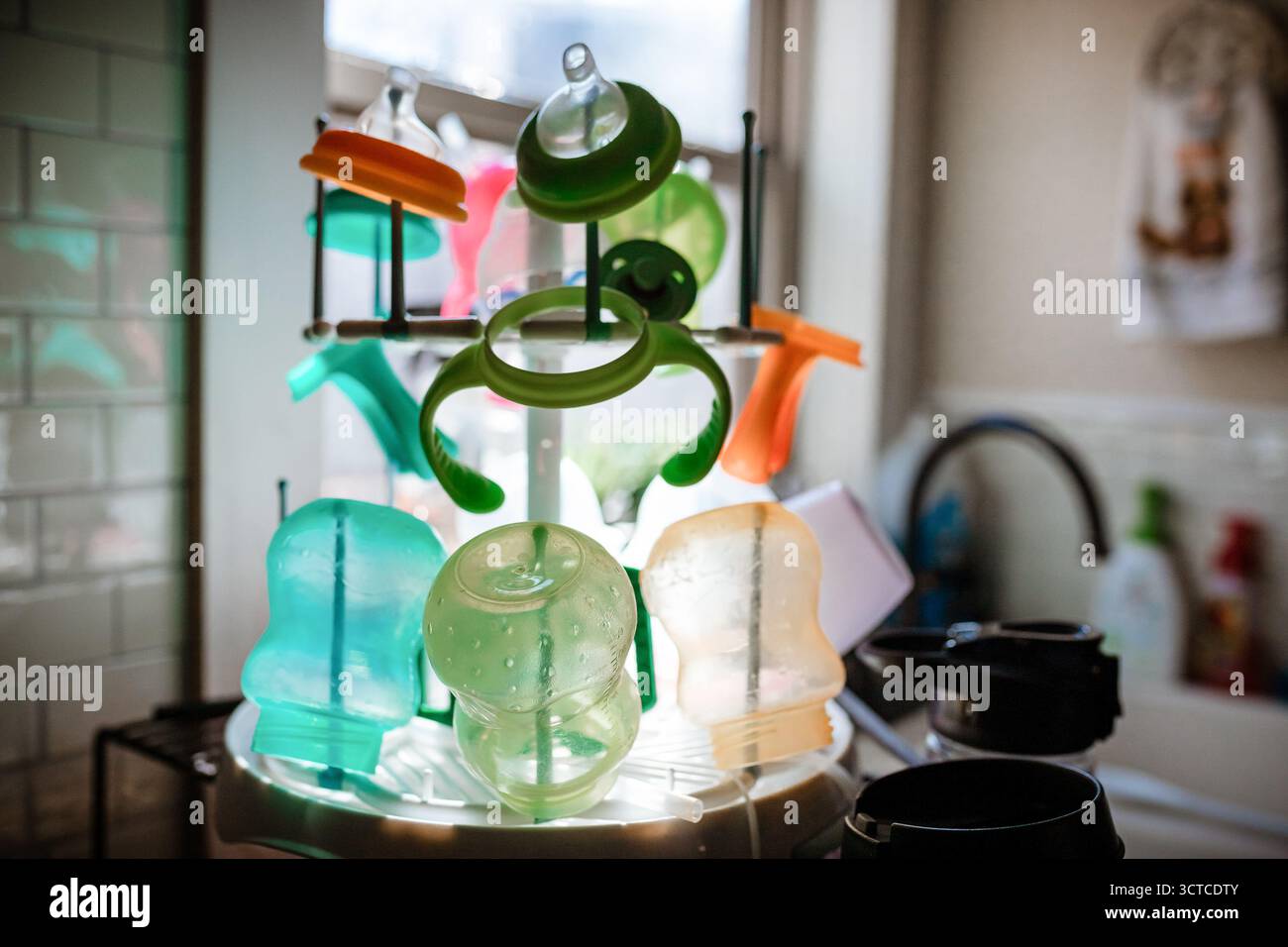 Colorful sippy cups on drying rack in kitchen Stock Photo