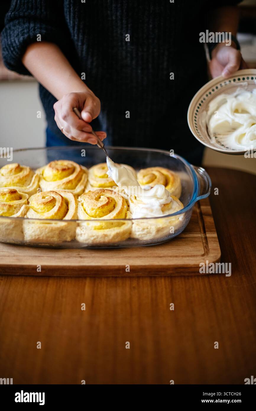 Spreading frosting on cinnamon rolls Stock Photo