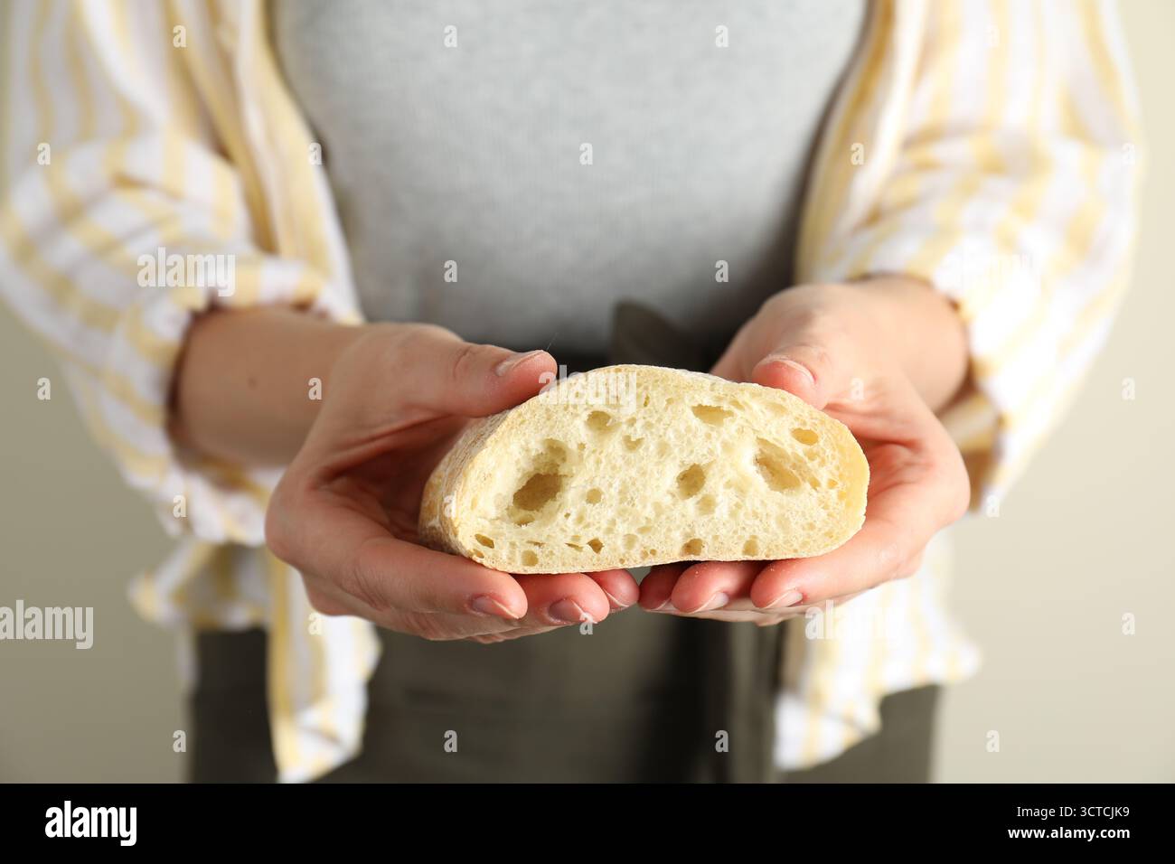 Woman holding half of fresh ciabatta on light background, closeup Stock Photo