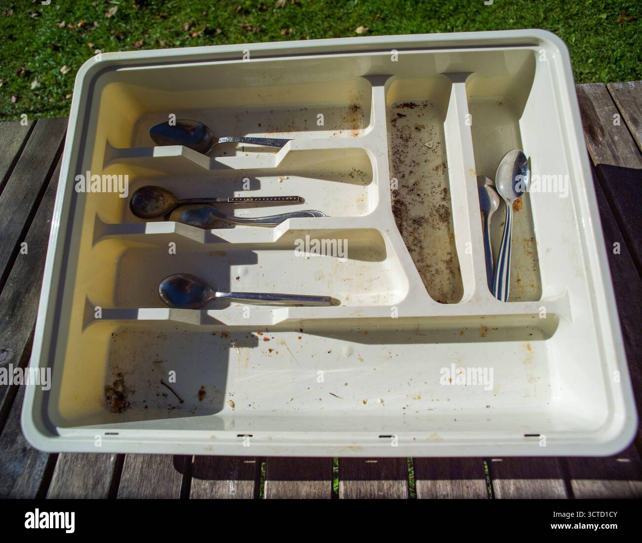 a messy drawer with silverware on the table needs to be cleaned Stock Photo