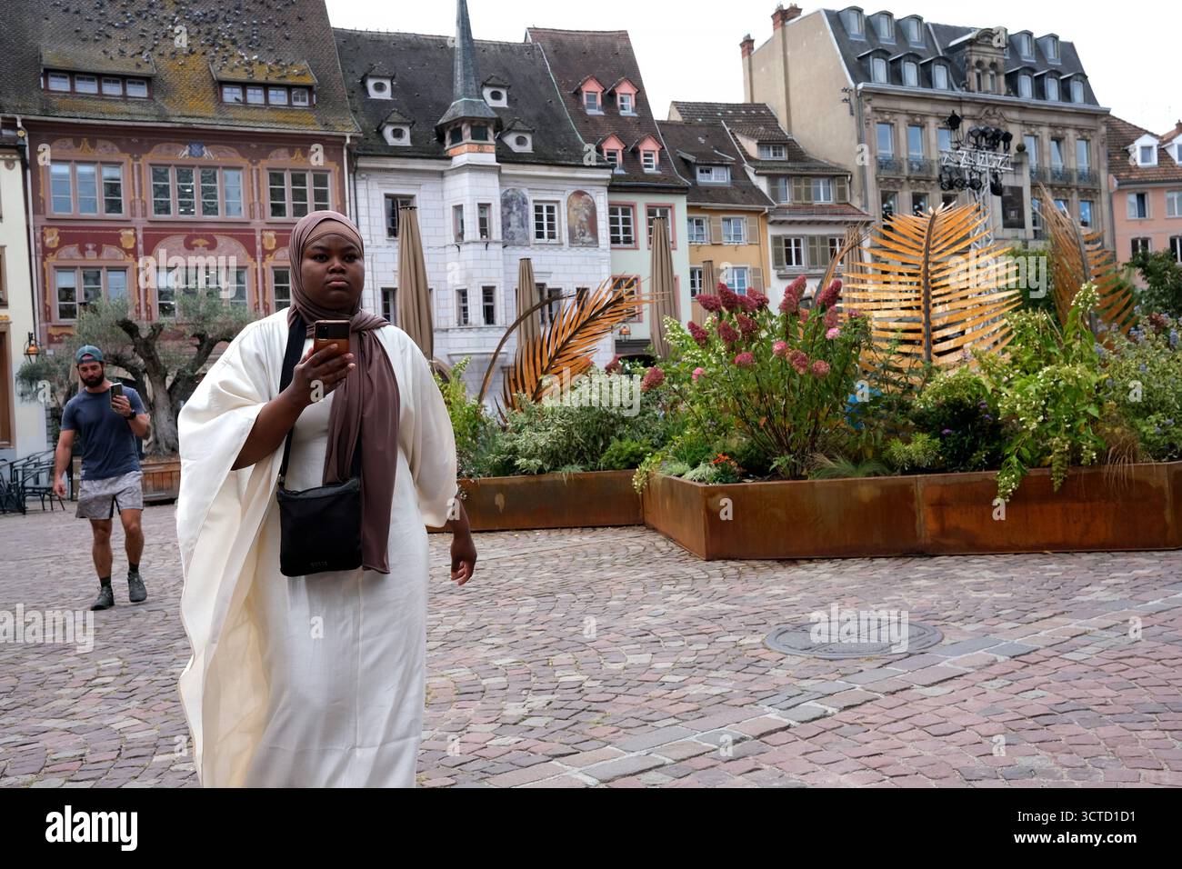 Woman using mobile phone while walking in Mulhouse, France. Stock Photo