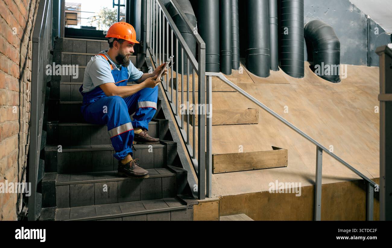 Technician using tablet on industrial staircase during break Stock Photo