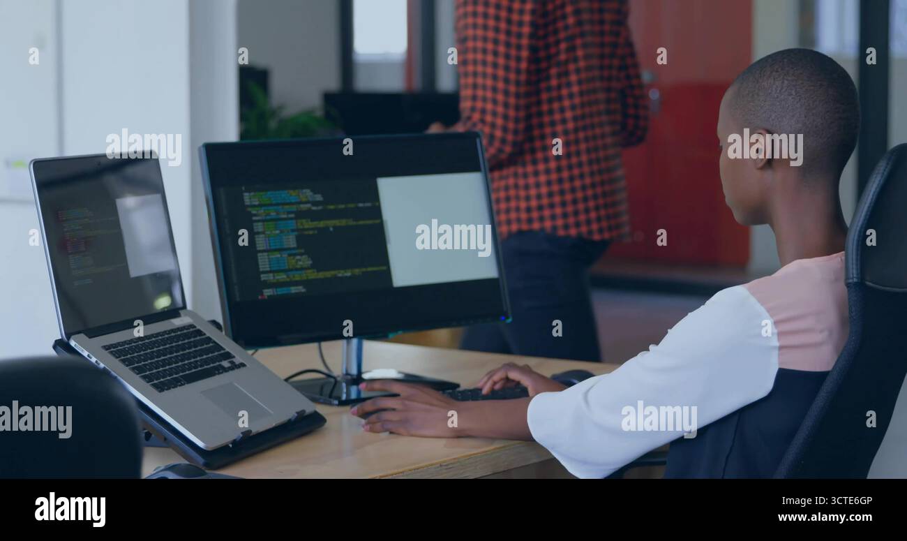 Coding female developer using laptop and external monitor in open-plan office, copy space Stock Photo