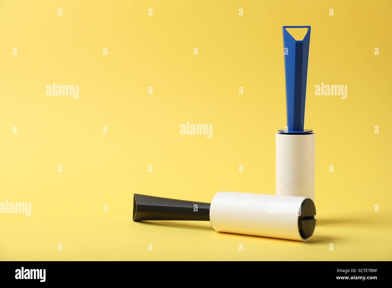Two lint rollers on yellow background, space for text Stock Photo