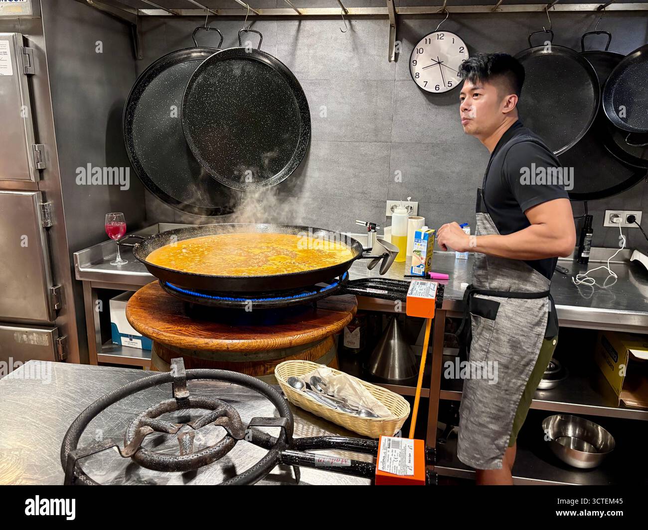 Spanish cooking class, learn to cook paella cooking class in Barcelona, chef instructor simmers paella over low gas flame, Spain,Europe - Smartphone Captured Stock Image