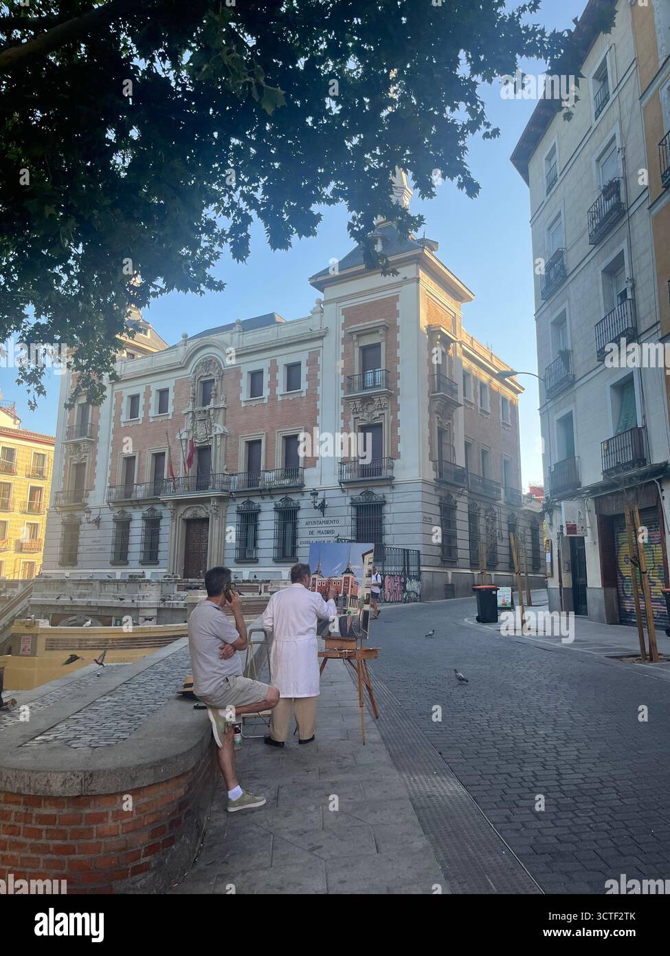 A street artist painting in the Barrio la Latina in Madrid, Spain, on a sunny summer day, with historic buildings, creating an urban scene. - Smartphone Captured Stock Image