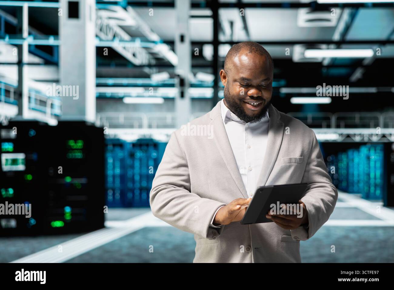 Happy data center engineer writing lines of code running on tablet, troubleshooting rackmounts. Cheerful IT professional using programming scripts on device in server room Stock Photo
