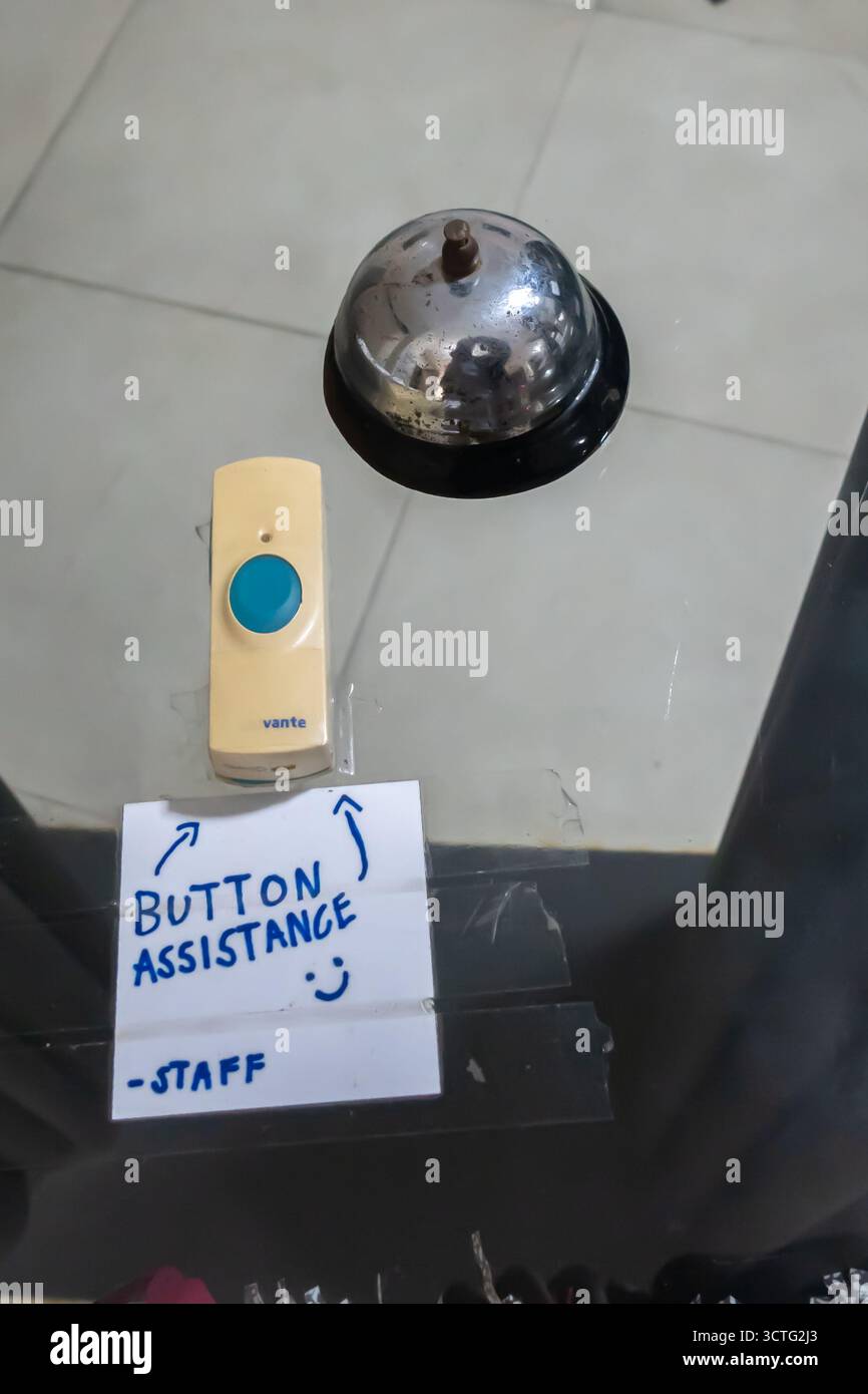 wireless doorbell push button and a traditional service bell, with a handwritten note Button assistance-Staff for a customer to request assistance Stock Photo