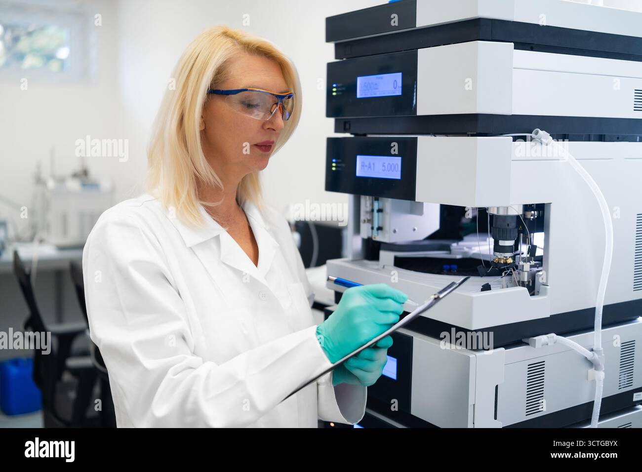 Laboratory worker taking notes during HPLC chromatography experiment in ...