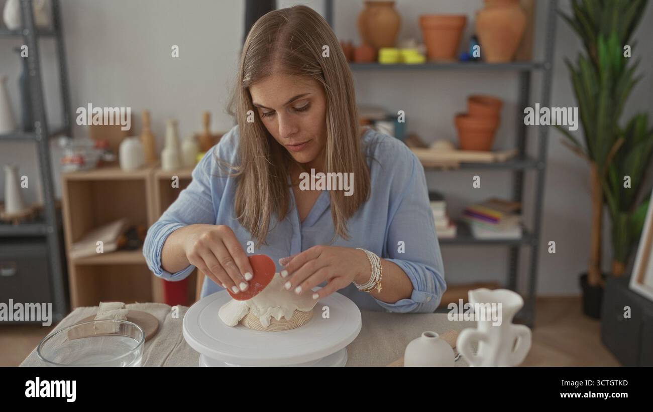 Blonde woman sculpts a ceramic vessel with her hands on a spinning ...