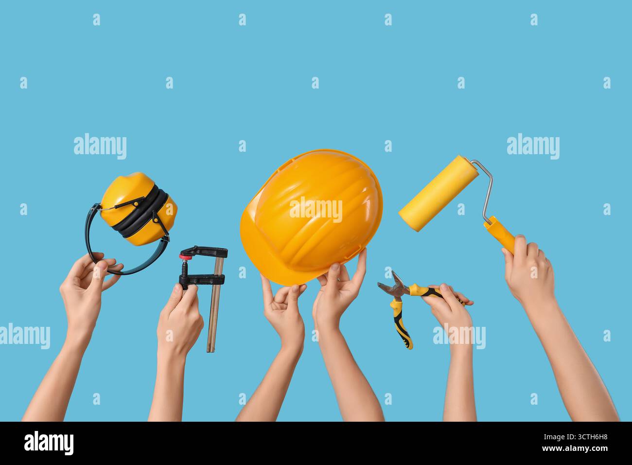 Hands with hardhat and construction tools on blue background Stock Photo