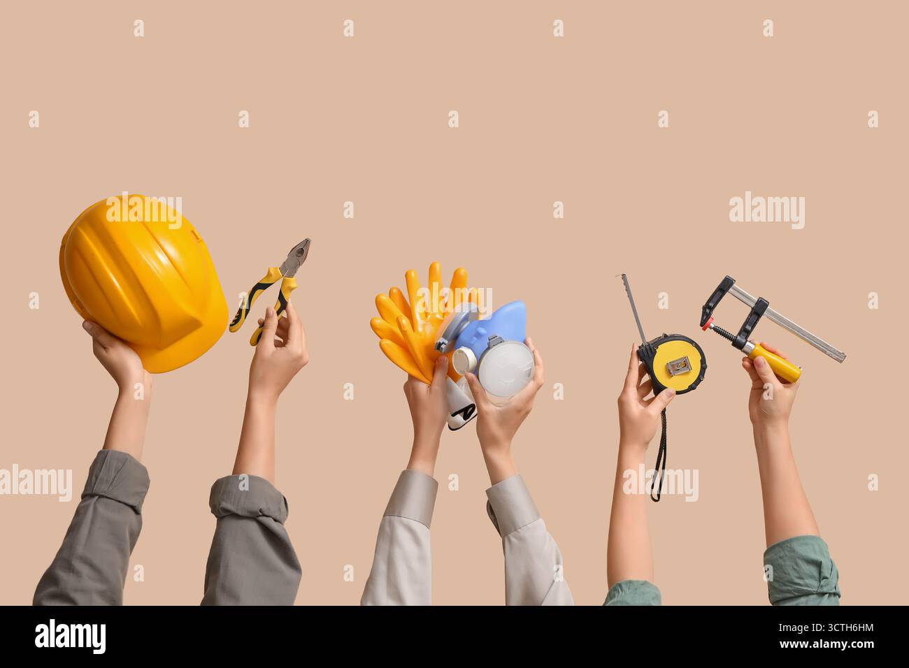 Hands with hardhat and construction tools on beige background Stock Photo