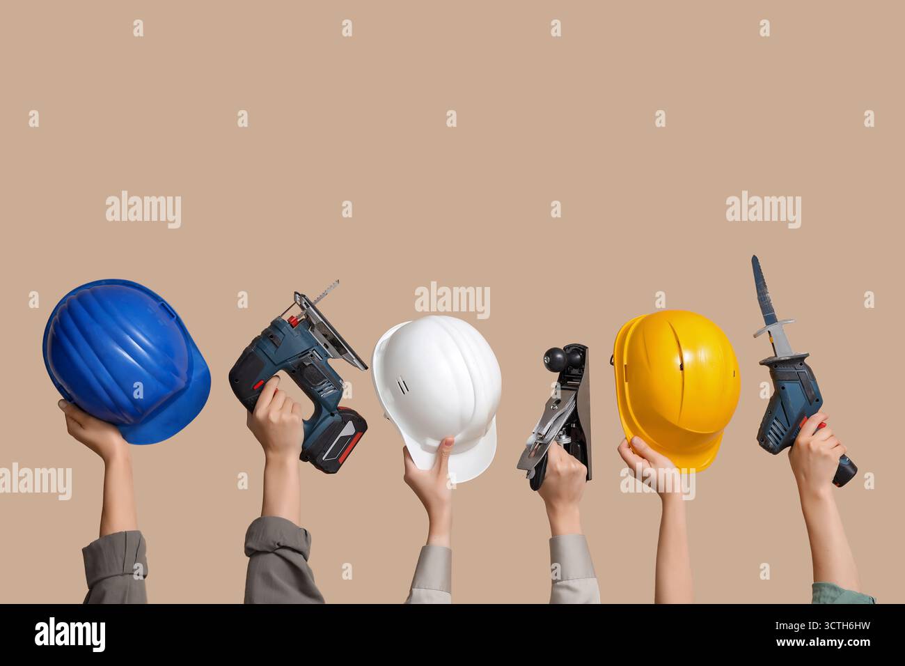 Hands with hardhats and construction tools on beige background Stock Photo