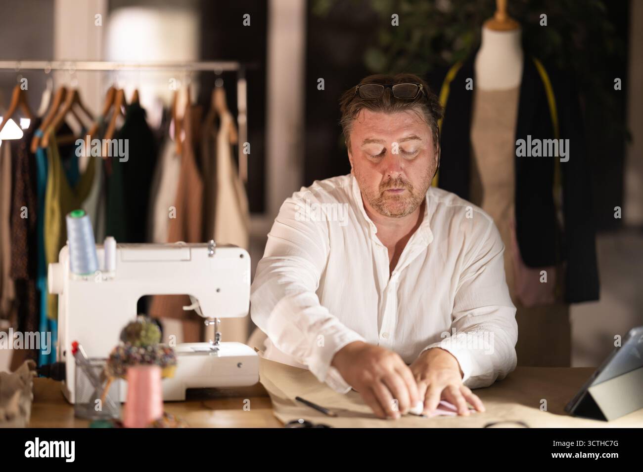 Middle-aged male dressmaker drawing detail on paper with chalk Stock Photo