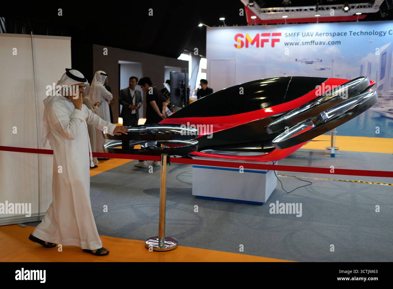 An Emirati visitor speaks on his mobile as he walks past a model of ...