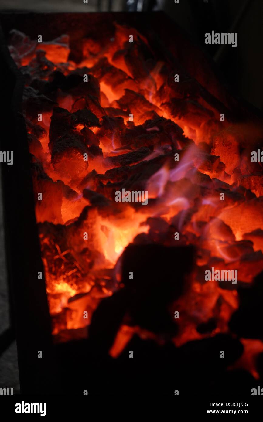 Vertical shot of glowing charcoal embers captured at night in Crete ...