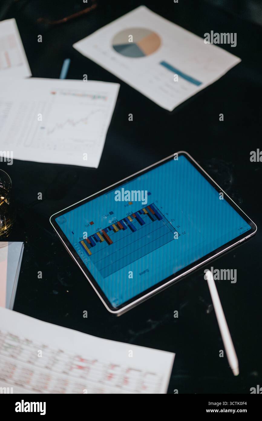 Tablet Displaying Data and Reports with Charts and Graphs on Workspace Stock Photo