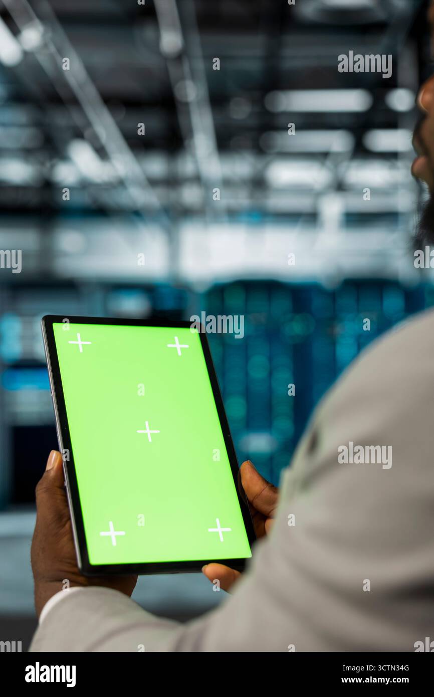 Server farm computer scientist using mockup tablet to repair equipment storing datasets. IT expert using green screen device to do debugging on mainframes doing computational operations Stock Photo